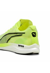 Zapatillas de correr de color amarillo neón con una parte superior de malla transpirable, acentos negros y una suela blanca acolchada que presenta el logotipo "NITRO" en el lateral.