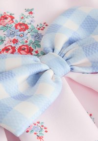 Helehallikasvalge ruuduline kangast vibu roosale kangale punaste ja lilla lillmustritega.