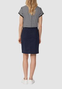 Marineblauwe denim pencil skirt met achterzakken, gecombineerd met een zwart-wit gestreepte top met korte mouwen en witte sneakers. Casual ontwerp.