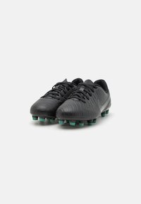 Svarte fotballsko med strukturert overflate, spisse knotter i turkis, og svarte lisser. Slank design med buet form.