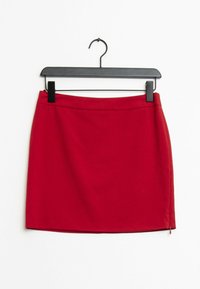 Röd A-linjeformad mini kjol tillverkad av slätt tyg, med en dold dragkedja på sidan och en ren, minimalistisk midjebanddesign.