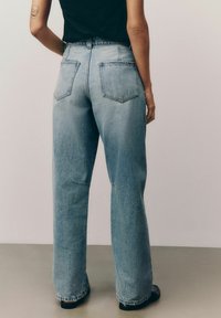 Lichtblauwe denim jeans met een hoge taille, wijd gesneden pijpen en twee achterzakken. Heeft een subtiele vervaagde textuur en een rechte zoom.