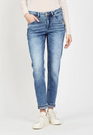 Hellblaue Jeans aus Denim mit geradem Bein, fünf Taschen und umgeschlagenen Säumen, kombiniert mit weißen Turnschuhen.