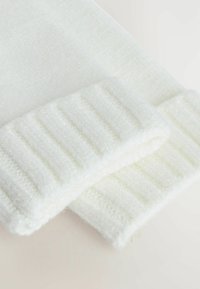 Biała dzianina o teksturowanym ściągaczu. Miękki, puszysty materiał o lekkim, przytulnym wyglądzie.