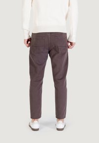 Pantalones marrón oscuro con corte recto, dos bolsillos traseros y tejido ligero, combinados con zapatillas blancas y un suéter de canalé color crema.