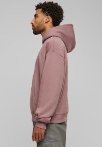 Sudadera con capucha en color rosa empolvado, que cuenta con un bolsillo tipo canguro, puños y dobladillo acanalados. Tejido suave con un corte relajado.