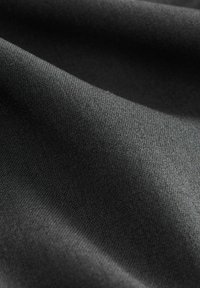Schwarzer Stoff mit einer glatten Textur, der einen subtilen Glanz und ein feines Webmuster aufweist. Leicht zerknittert, was Falten und Konturen zeigt.