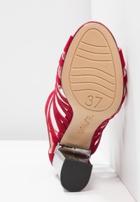 Sandale rouge à talons hauts avec lanières, semelle texturée indiquant la taille 37, dotée d'un talon carré et de la marque "unisa" sur la semelle.