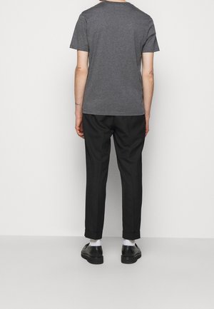 Grå bomuld t-shirt med korte ærmer, kombineret med sorte skræddersyede bukser med op rullede manchetter og sorte sko. Simpelt og moderne design.