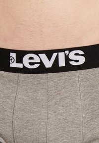 Harmaat kangasbokserit, joissa on musta joustava vyötärönauha, jossa on valkoinen "Levi's"-logo, ja litteät saumat mukavuutta ja istuvuutta varten.
