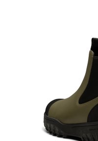 Botte en caoutchouc verte avec un bout en cuir texturé noir, panneau latéral élastique et semelle robuste. Présente un matériau lisse et un design minimaliste.