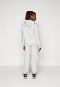 Gray sweatshirt with a hood and gray sweatpants. Smooth fabric, relaxed fit, drop shoulders. Shoes: black with pink and purple accents.