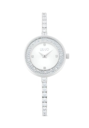 Montre en argent avec un cadran rond, accents en cristal clair autour de la lunette et du bracelet, et un cadran blanc minimaliste avec des aiguilles et un logo en argent.