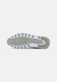 Weiße Sneaker-Sohle mit grauem Gummi-Traktionsmuster und Reebok-Logo. Mit einem wellenartigen Design und erhabenen, runden Erhebungen für besseren Halt.