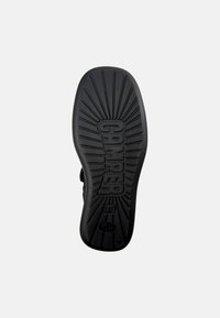 Sole in gomma nera con un motivo a righe, logo "CAMPER" in rilievo, taglia "38" e linee radiali per una maggiore trazione.