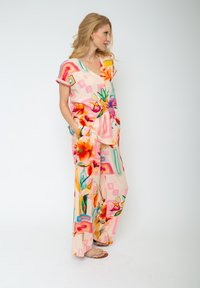 Blumenmuster, weiches Stoffoutfit in Koralle- und Pastellfarben. Verfügt über einen V-Ausschnitt, kurze Ärmel und eine weit geschnittene Hose mit Taschen.