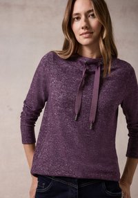 Lila langärmliger Pullover mit strukturiertem Finish, einem hohen Kragen, Kordelzügen und Zubehör aus Silber.