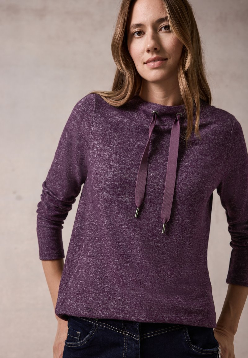 Lila langärmliger Pullover mit strukturiertem Finish, einem hohen Kragen, Kordelzügen und Zubehör aus Silber.