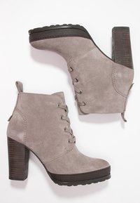 Grå nubuck ankelstøvler med en kraftig hæl, med metaløjer og snørebånd, struktureret gummisål og glatte læderdetaljer.