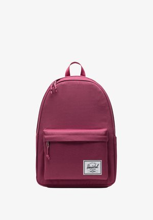 Mauve Herschel ryggsäck med rundad form, framficka med dragkedja, dubbla dragkedjehandtag och en vävd märkesetikett på den nedre framsidan.
