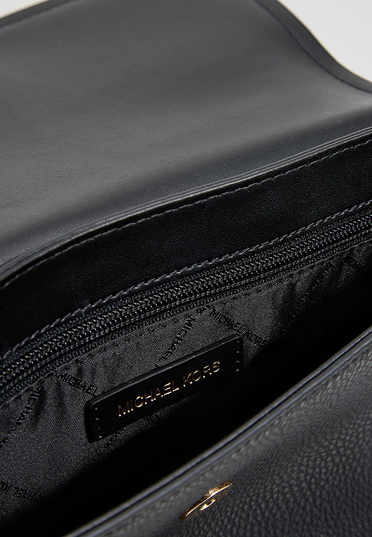 Bolso de mano de cuero negro con una superficie texturizada, cierre de cremallera y un forro que presenta un estampado repetido de logotipo. Acentos de hardware dorado visibles.