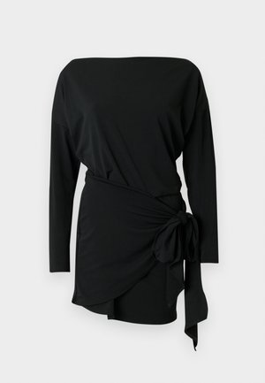 Abito nero a maniche lunghe in tessuto morbido, con scollo a barca e dettaglio con laccio laterale in vita, arricchito da un orlo a drappeggio.