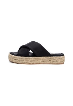 Zwarte slipper met brede gekruiste bandjes en dikke gevlochten jute plateauzool tegen een witte achtergrond.
