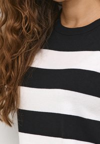 Sorte og hvide stribede sweater med rund hals; lavet af bomuldsstof med en blød tekstur; synlige ribbede kanter ved halsudskæringen.