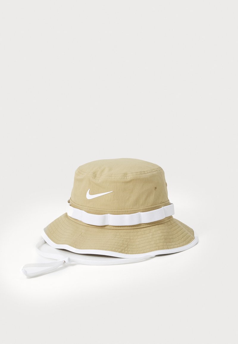 Beige emmerhoed van gestructureerde stof met een brede rand, voorzien van een witte accentband en een wit Nike-logo op de voorkant.