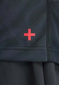 Camiseta deportiva negra con tejido de malla texturizado, con un logo de signo más rojo en la manga. Diseño sencillo y funcional.