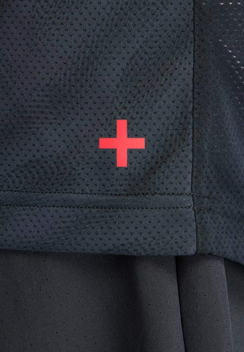 Schwarzes Sportshirt aus strukturiertem Netzstoff mit einem roten Pluszeichen-Logo auf dem Ärmel. Einfaches und funktionales Design.