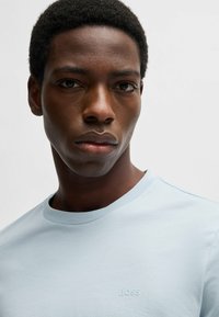 Light blue cotton t-shirt with a crew neck and short sleeves, featuring a subtle embossed "BOSS" logo on the front.