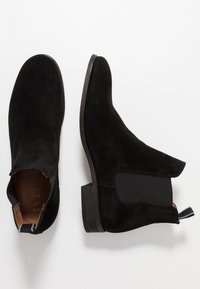 Bottines en daim noir avec des panneaux latéraux élastiques et une petite languette. Dotées d'un petit talon bloc et d'une doublure intérieure lisse.