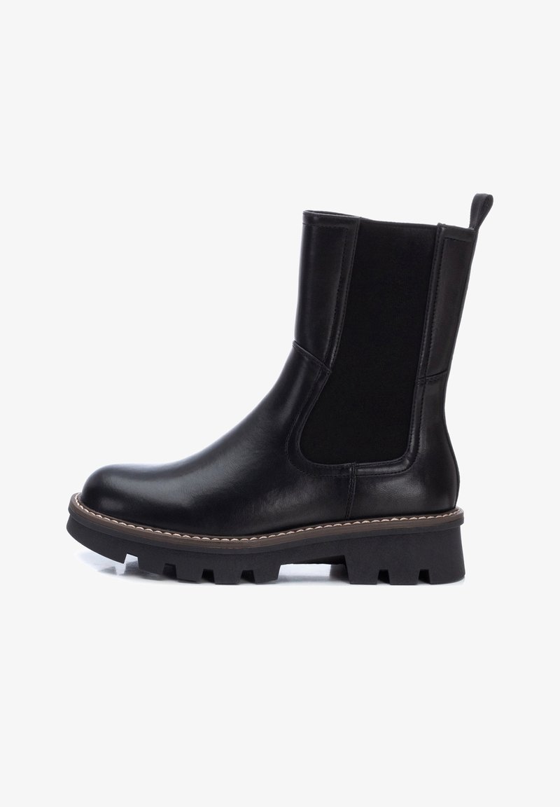 Botte Chelsea en cuir noir avec panneaux latéraux élastiques, languette à l'arrière, semelle épaisse et robuste, et coutures contrastées autour du bord de la semelle.
