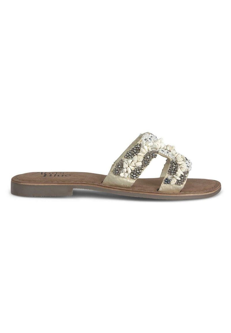 Sandales beiges avec deux bandes décoratives ornées de perles blanches et grises. Semelle souple avec un profil bas et une semelle intérieure texturée.