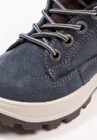 Blaue Wildlederstiefel mit runden Metallösen, kontrastierenden Nähten und einer strukturierten Gummisohle mit ausgeprägten Profilnoppen.