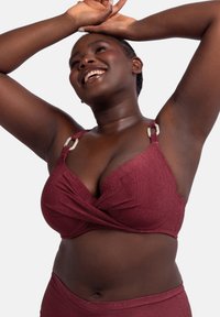 Burgundska bralette s teksturiranim materijalom, s prevrnutim prednjim dizajnom i kremastim metalnim detaljima na trakama.