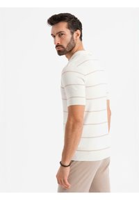 Krátký rukáv, přiléhavá košile v bílé barvě s jemnými růžovými vodorovnými pruhy, vyrobená z pleteného materiálu. Zahrnuje kulatý výstřih a žebrovaný lem.