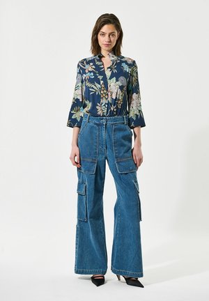 Navy blouse met bloemenpatroon en 3/4 mouwen, gecombineerd met hoge, wijdvallende blauwe denim cargo broek met meerdere zakken.