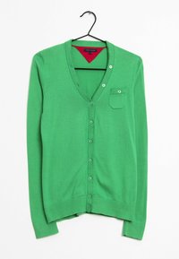 Zelený pletený kardigan s výstřihem do V, pěti knoflíky a náprsní kapsou; hladká textura; dlouhé rukávy; zavěšený na černém háčku.