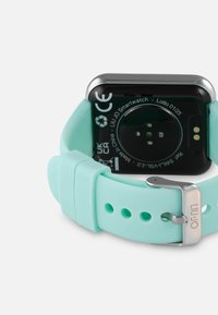 Smartwatch Liu Jo má obdĺžnikový čierny ciferník, mätovú silikónovú pásku s nastaviteľnou striebornou sponou a okrúhle senzorové detaily na zadnej strane.