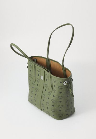 Zielona torba na ramię wykonana z teksturowanego materiału, z wzorem logo, podwójnymi uchwytami oraz kontrastowym jasnobrązowym wnętrzem.