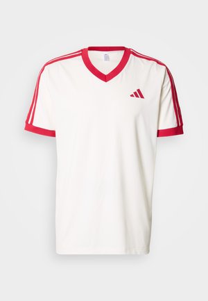 Hvid T-shirt med korte ærmer og V-hals, røde detaljer på ærmer og krave, tre røde striber på hver skulder og et logo på brystet.