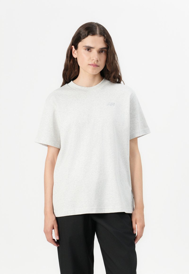T-shirt en coton gris clair avec un col rond, des manches courtes et un petit logo imprimé sur la poitrine. Coupe décontractée et ample.