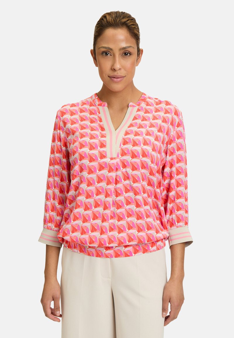 Blusa colorata con motivo geometrico in rosa e arancione, con scollatura a V e maniche a tre quarti, realizzata in tessuto leggero.