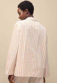 Lichtgewicht gestreepte blazer in zacht beige en wit, met een relaxte pasvorm, lange mouwen en een klassieke kraag. Soepele stoftextuur.