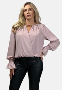 Różowa satynowa bluzka z długimi rękawami i marszczonymi mankietami. Posiada szczegół w postaci łańcuszka przy dekolcie oraz krzyżowy projekt z przodu.