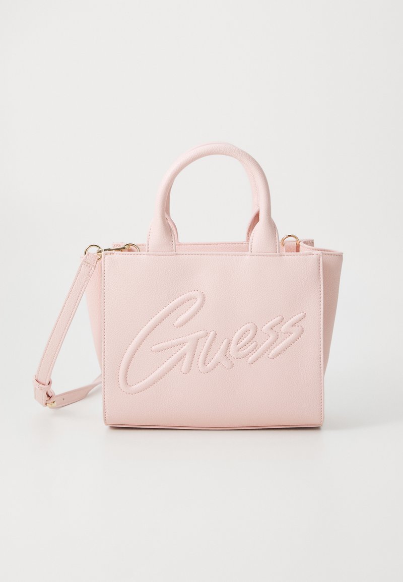 Różowa syntetyczna torba na ramię z haftowanym logo "Guess", podwójnymi uchwytami i odczepianym paskiem na ramię. Strukturalny design, gładka tekstura.