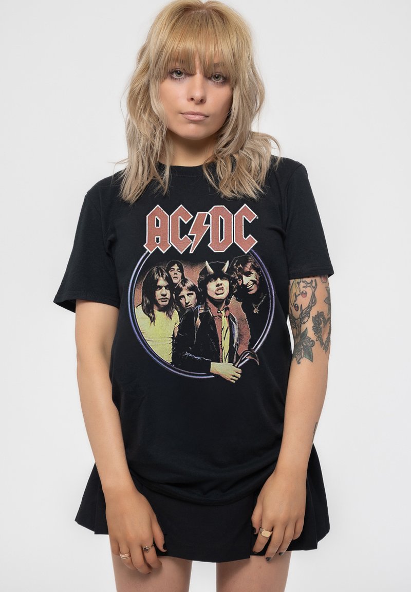Black cotton t-shirt featuring a colorful AC/DC graphic print of band members in a circular design. Model wears a black skirt.