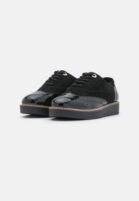 Scarpe nere realizzate con materiali misti, caratterizzate da pelle verniciata liscia e suede testurizzato, punta arrotondata, sei occhielli e suola piatta.